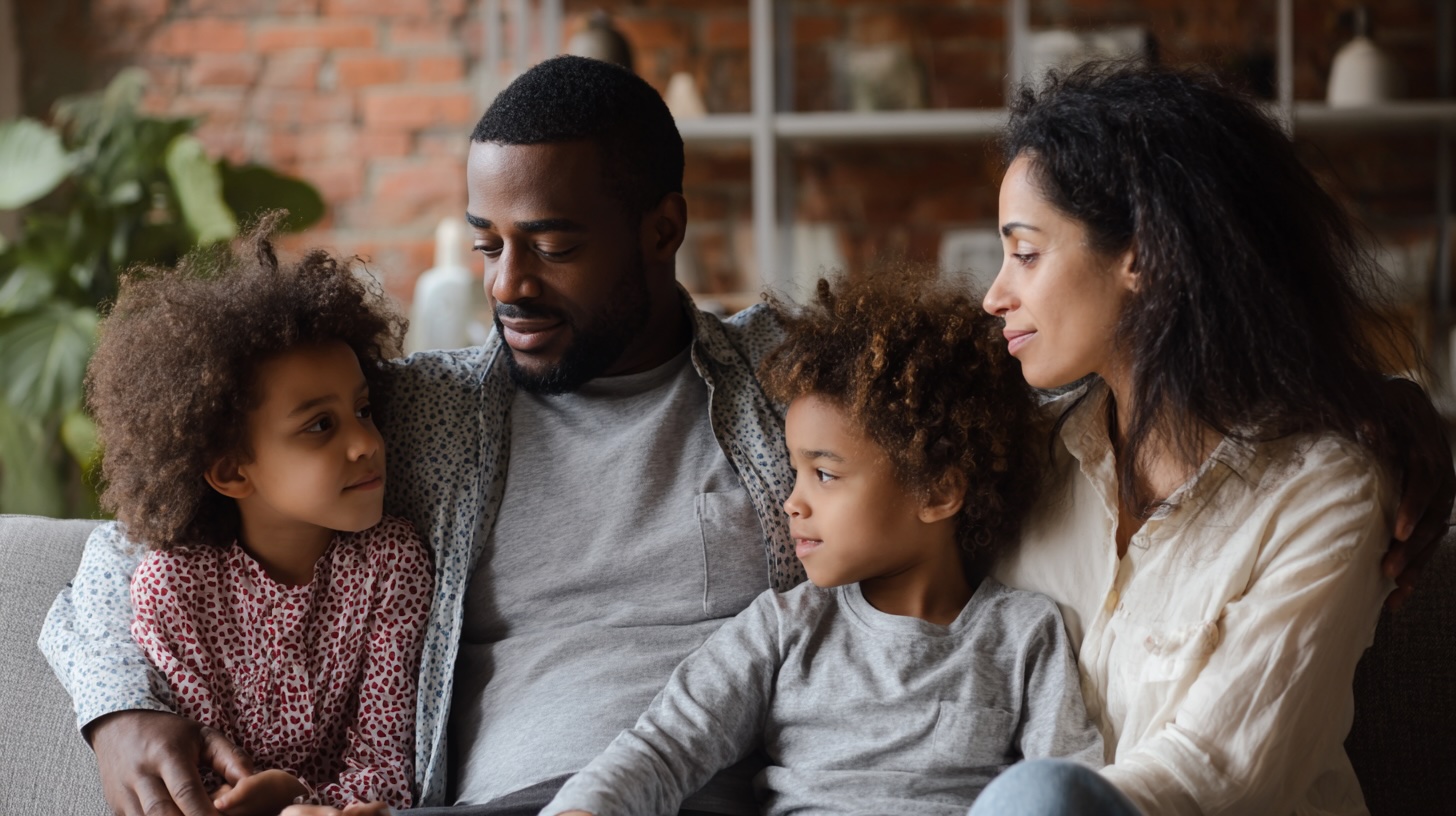 men can go to therapy a man sitting with his family. his arm is around his children. his wife is looking at him. --ar 16:9 --v 7 Job ID: fdcaf0d4-f0aa-4aa3-b8bb-26edf83ed2f5